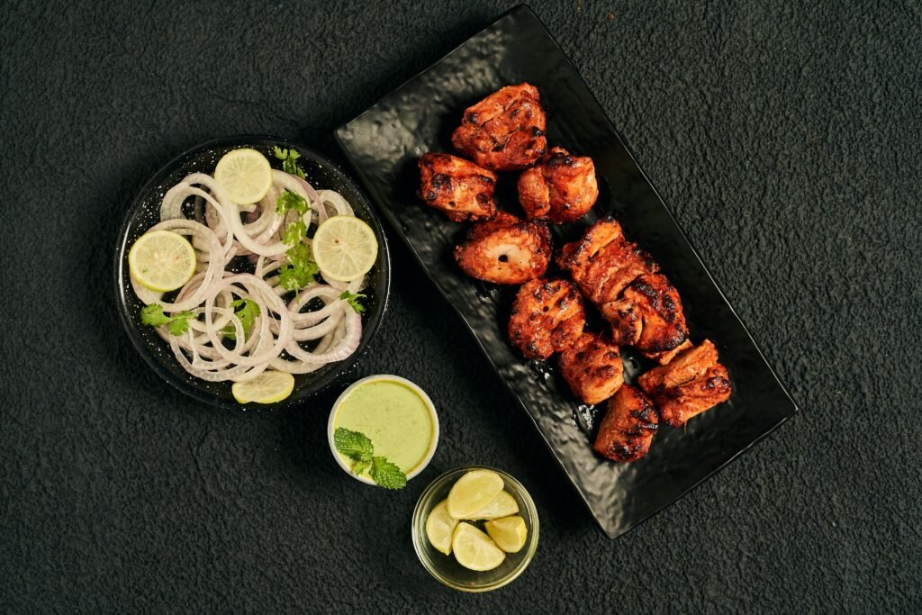 Flat lay of juicy tandoori chicken pieces with onion salad and green chutney, perfect for Indian cuisine lovers.