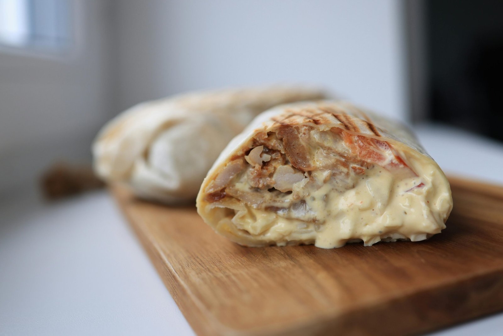 pexels-photo-15913640-15913640 Tasty chicken wrap filled with creamy sauce on a wooden cutting board.