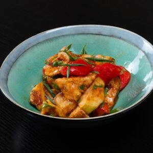 A mouth-watering stir-fried chicken dish with colorful vegetables in a bowl.