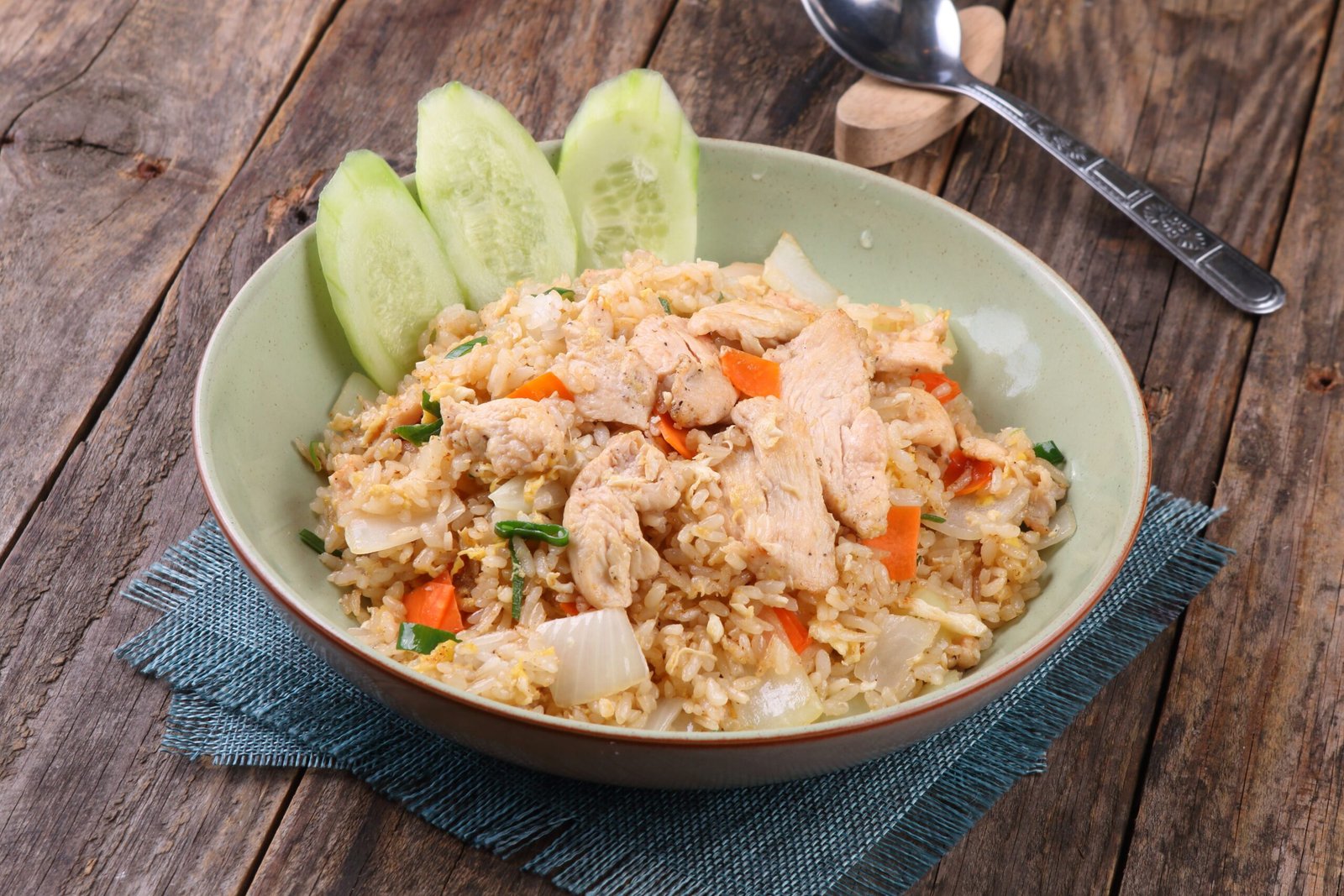 pexels-photo-34668501-34668501 A bowl of chicken fried rice with fresh vegetables on a rustic wooden table.