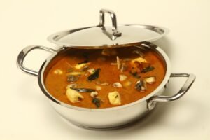 A tempting Indian curry served in a shiny stainless steel pot, perfect for food photography and culinary promotions.