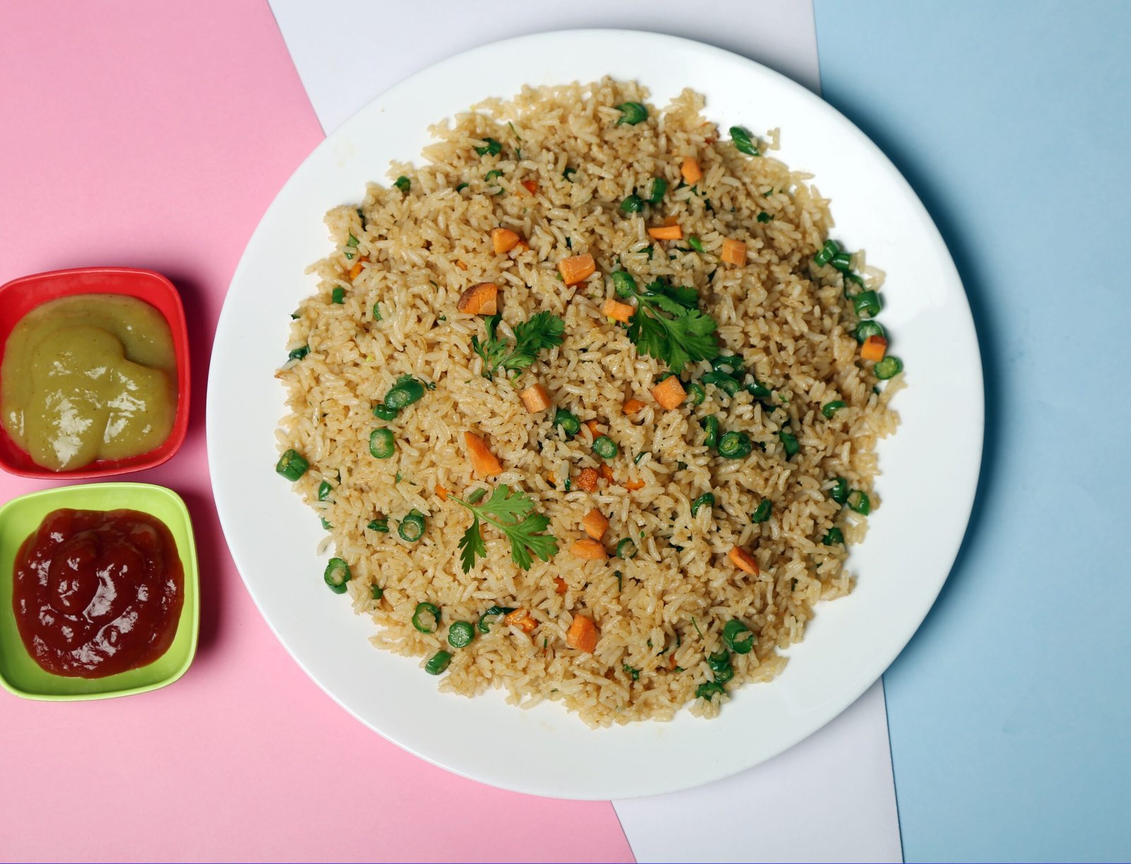 pexels-photo-35071826-35071826 Delicious vegetable fried rice served with green and red sauces, displayed on a colorful background.