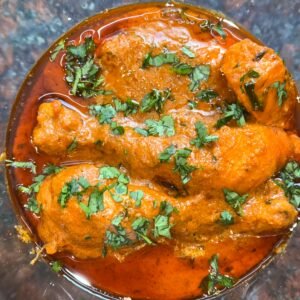 Close-up of a spicy chicken curry dish topped with fresh cilantro, perfect for Indian cuisine enthusiasts.