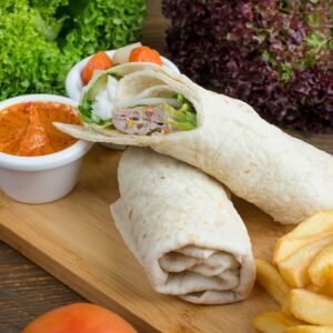 Tasty wraps served with fries and a spicy dip on a wooden platter.