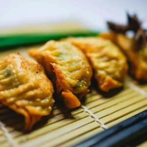 Delicious fried gyoza dumplings arranged on a bamboo mat with chopsticks nearby.