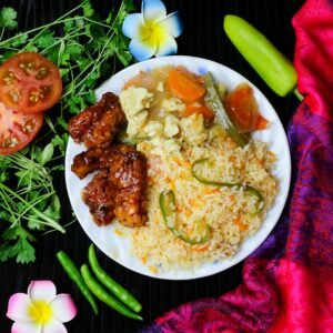 Delicious Asian fusion meal featuring fried rice with veggies and glazed chicken wings, styled against colorful background.