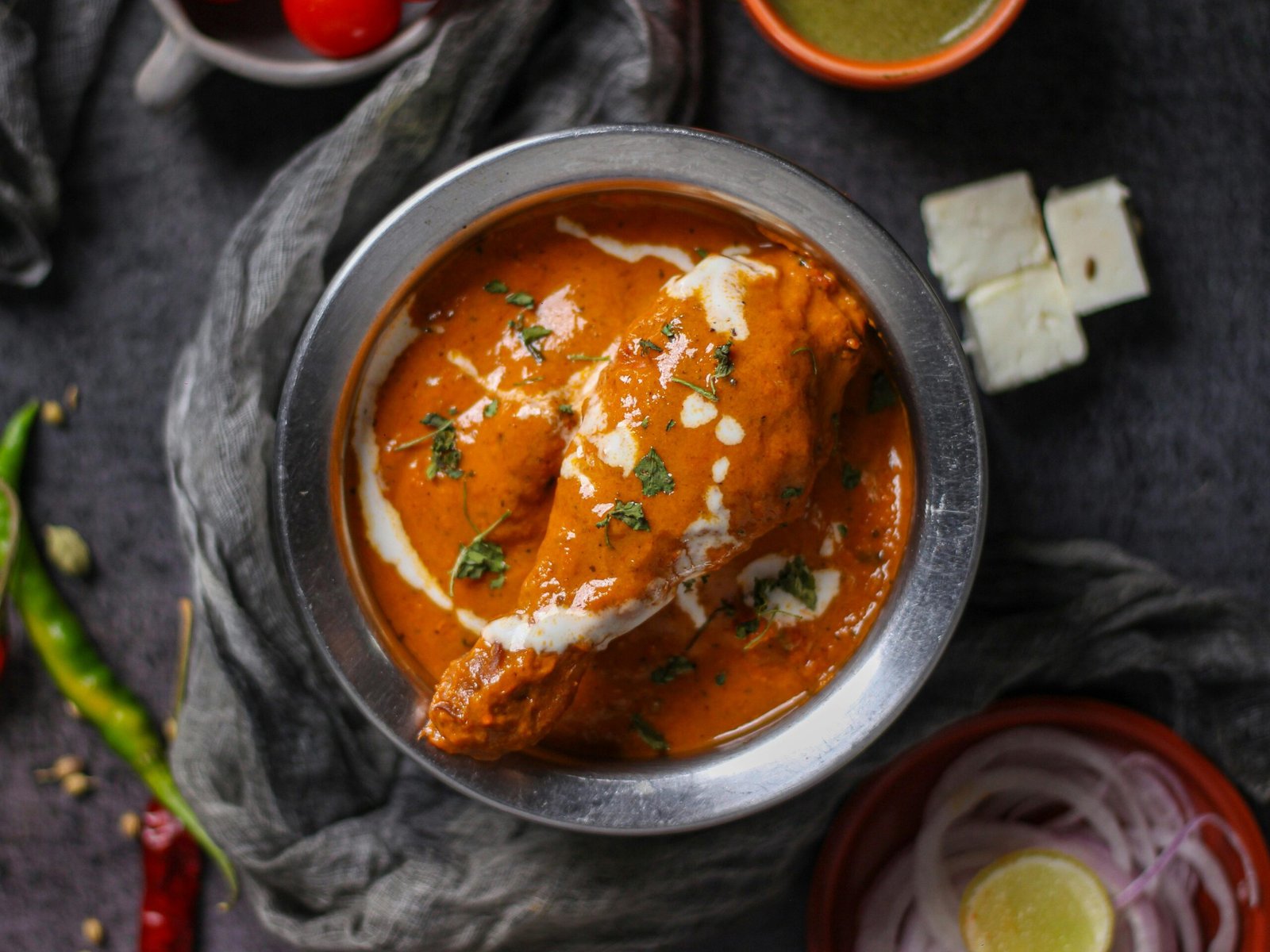 pexels-photo-9609844-9609844 Mouth-watering butter chicken curry garnished with cream and herbs, served in a stainless steel bowl.
